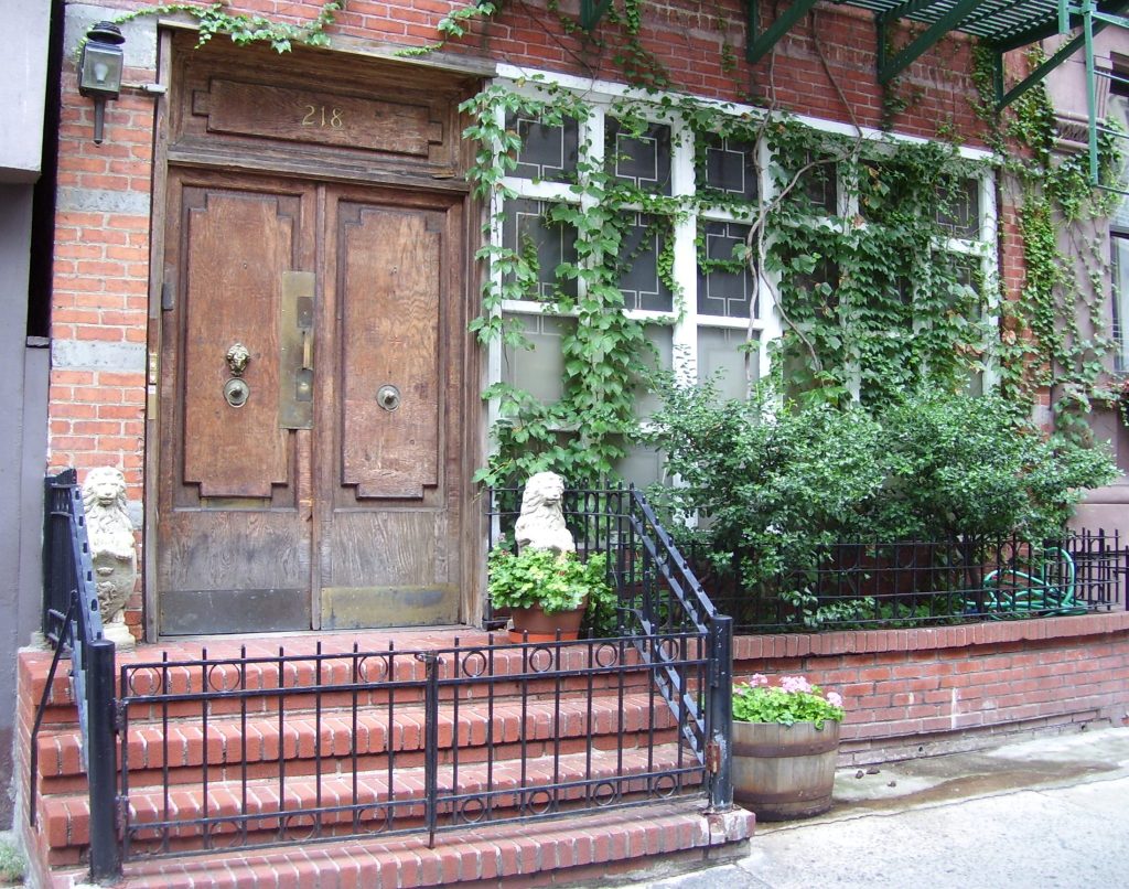 The entrance of Casa Clara at 218 East 25th Street: wooden double doors, brick steps, and plaster lions